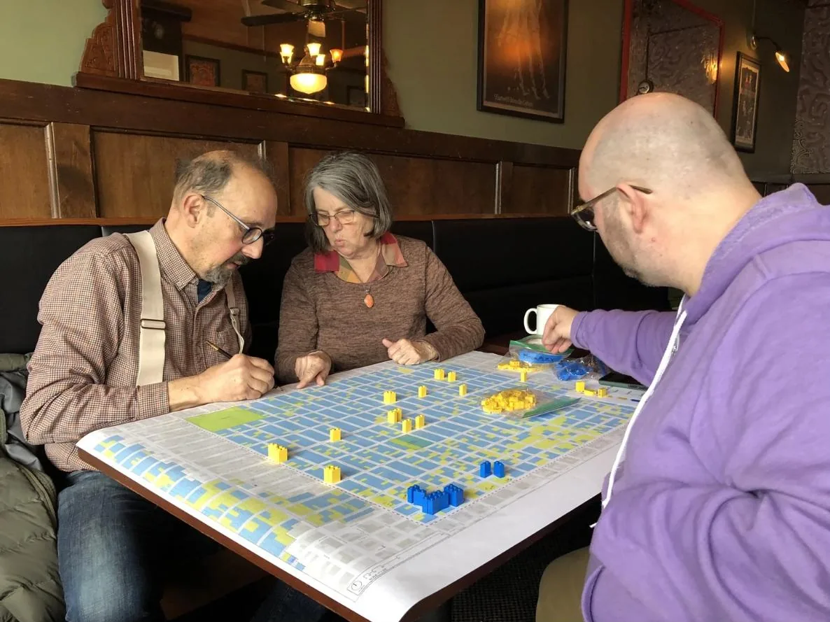 Three neighbors at a table placing Lego pieces on the Irvington map